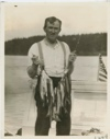 Image of Martin Vorse (cook) standing on the cabin of Seeko with trout caught in Frank's